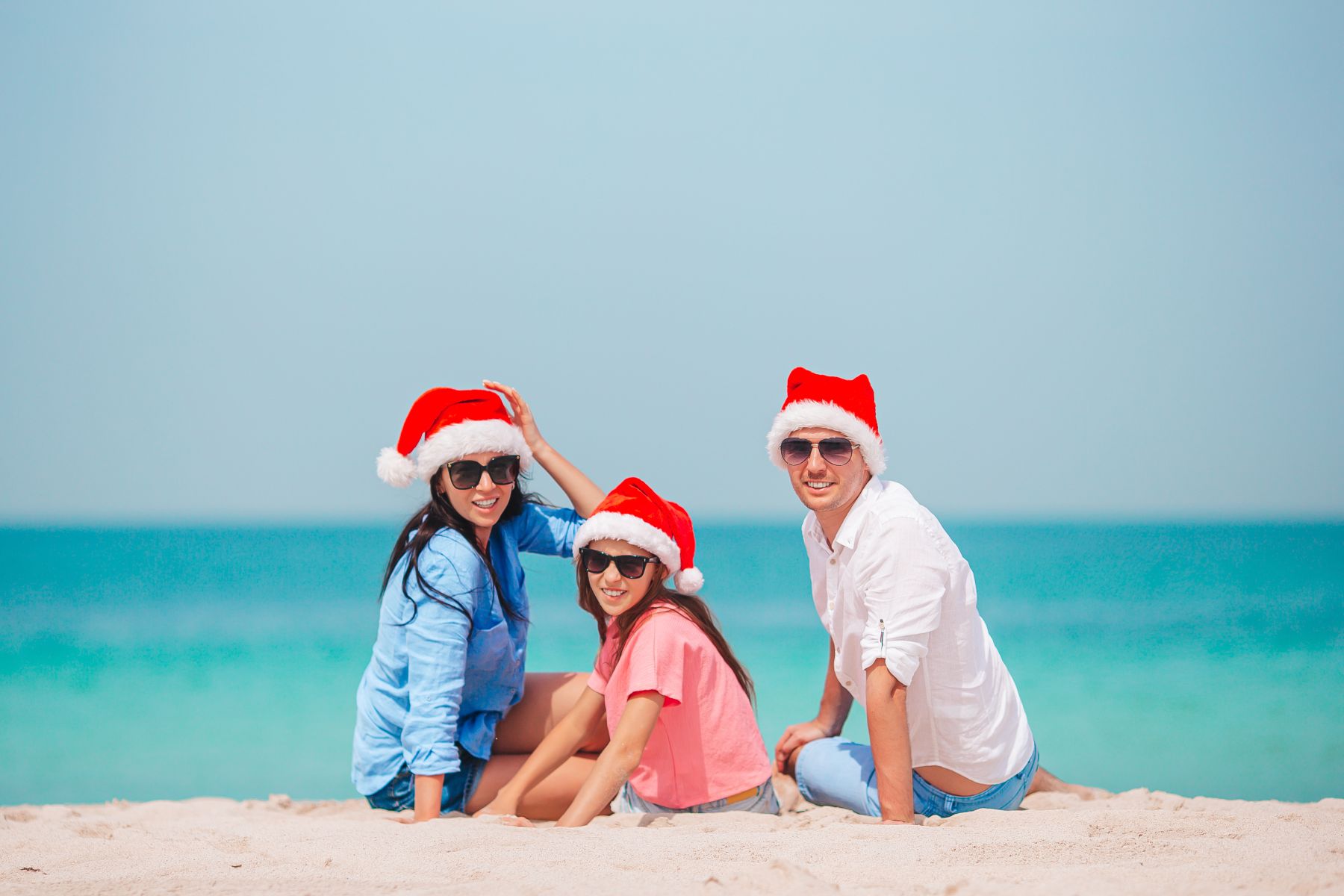 family in santa hats on beach
